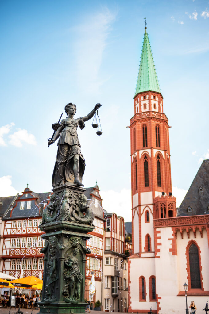 Vertical view of the Fountain Of Justice located in the Roemerberg, Frankfurt, Germany. Old St. Nicholas Church on the background