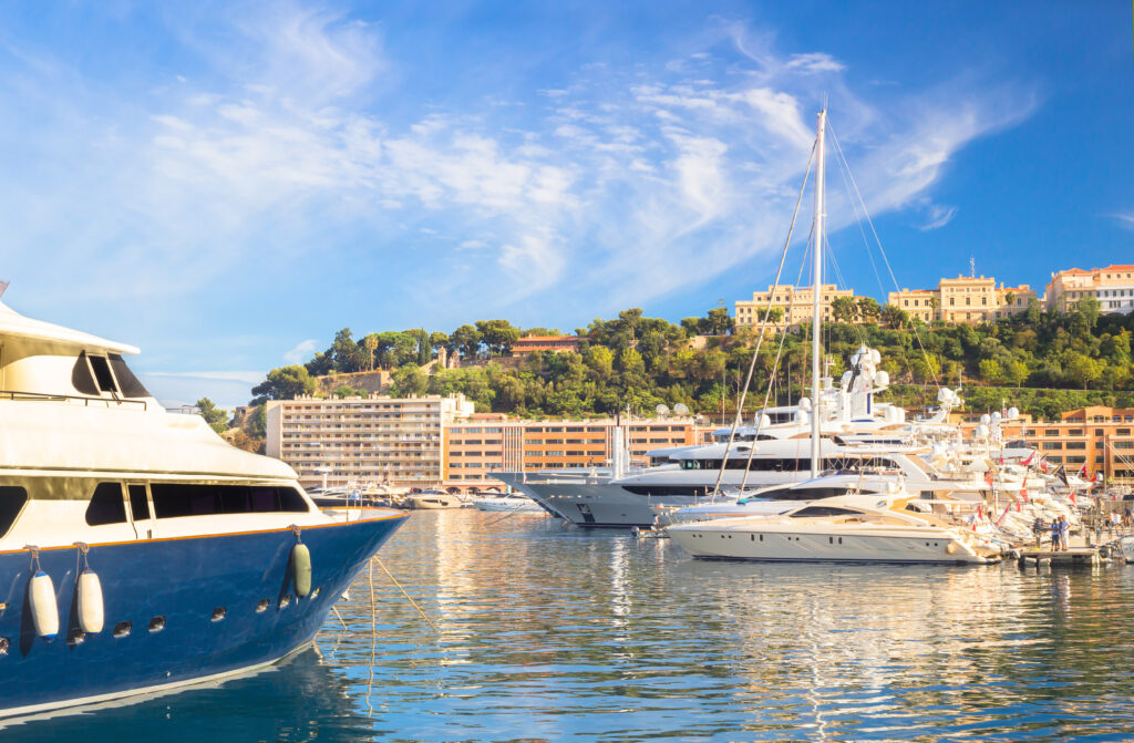 Yacht Club de Monaco. Yachts in Monaco harbor. Expensive luxury yachts in harbor of Monaco principality. Beautiful landscape with clear water and blue sky.